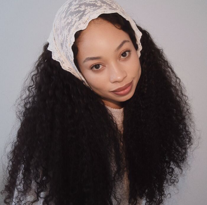Orie with long curls in a lace headscarf